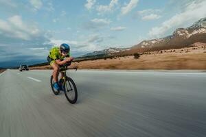 full längd porträtt av ett aktiva triathlete i sportkläder och med en skyddande hjälm ridning en cykel. selektiv fokus foto