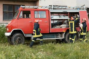 grupp av brand kämpar stående självsäker efter en väl Gjort rädda drift. brandmän redo för nödsituation service. foto