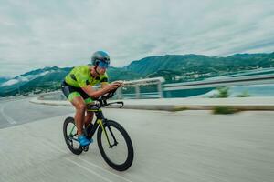 full längd porträtt av ett aktiva triathlete i sportkläder och med en skyddande hjälm ridning en cykel. selektiv fokus foto