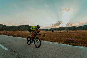 full längd porträtt av ett aktiva triathlete i sportkläder och med en skyddande hjälm ridning en cykel. selektiv fokus foto