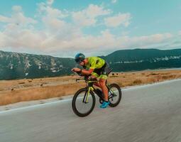 full längd porträtt av ett aktiva triathlete i sportkläder och med en skyddande hjälm ridning en cykel. selektiv fokus foto