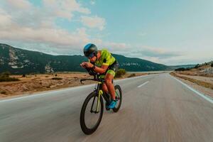 full längd porträtt av ett aktiva triathlete i sportkläder och med en skyddande hjälm ridning en cykel. selektiv fokus foto