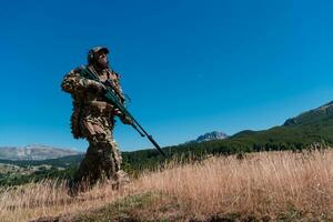 armén soldat innehav en prickskytt gevär med omfattning och gående i de skog. krig, armé, teknologi och människor begrepp. foto