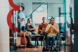 affärskvinna i rullstol har företag möte med team på modern kontor. en grupp av ung frilansare hålla med på ny uppkopplad företag projekt foto