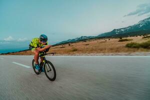 full längd porträtt av ett aktiva triathlete i sportkläder och med en skyddande hjälm ridning en cykel. selektiv fokus foto