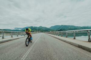 full längd porträtt av ett aktiva triathlete i sportkläder och med en skyddande hjälm ridning en cykel. selektiv fokus foto