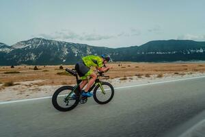 full längd porträtt av ett aktiva triathlete i sportkläder och med en skyddande hjälm ridning en cykel. selektiv fokus foto