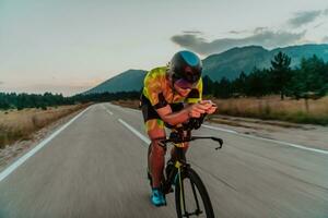 natt kör. full längd porträtt av ett aktiva triathlete i sportkläder och med en skyddande hjälm ridning en cykel i natt tid.. selektiv fokus foto