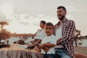 de familj spenderar tid med deras barn medan ridning hästar tillsammans på en sandig strand. selektiv fokus foto