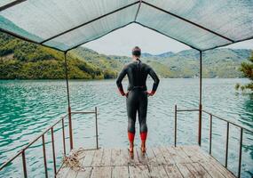 idrottare sätta på en simning kostym och framställning för triathlon simning och Träning i de flod omgiven förbi naturlig grönska foto