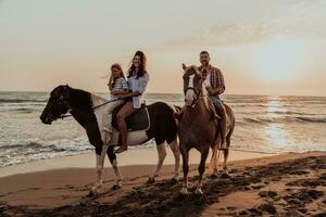 de familj spenderar tid med deras barn medan ridning hästar tillsammans på en sandig strand. selektiv fokus foto