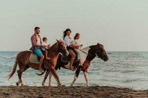 de familj spenderar tid med deras barn medan ridning hästar tillsammans på en sandig strand. selektiv fokus foto