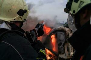 brandmän bekämpa de brand flamma till kontrollera brand inte till spridning ut. brandman industriell och offentlig säkerhet begrepp. trafik eller bil olycka rädda och hjälp handling. foto