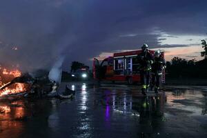 brandmän bekämpa de brand flamma till kontrollera brand inte till spridning ut. brandman industriell och offentlig säkerhet begrepp. trafik eller bil olycka rädda och hjälp handling. foto