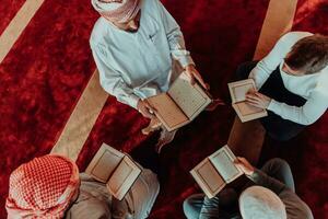 en grupp av muslims läsning de helig bok av de quran i en modern moské under de muslim Semester av ramadan foto