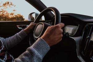 stänga upp man hand körning en bil på solnedgång. de begrepp av bil resa foto