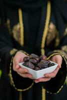 modern muslim kvinna innehav en tallrik full av ljuv datum på iftar tid i ramadan kareem islamic friska mat begrepp UFO grön bakgrund foto