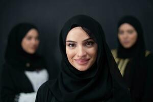 grupp porträtt av skön muslim kvinnor i en modern klänning med hijab isolerat på svart bakgrund foto