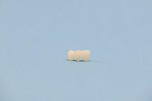 metall fri keramisk tänder implantera dental kronor isolerat på en blå bakgrund. foto