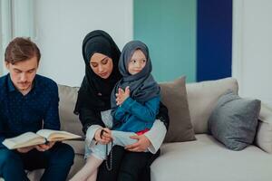 Lycklig muslim familj njuter de helig månad av ramadan medan bön- och läsning de quran tillsammans i en modern Hem foto