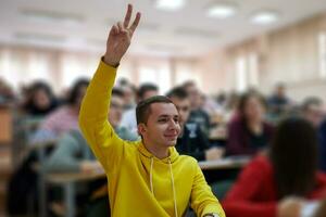 de studerande höjer hans händer be en fråga i klass i högskola foto