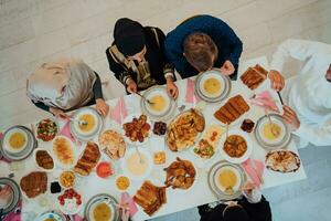 topp se av muslim familj har iftar middag dricka vatten till ha sönder fest. äter traditionell mat under ramadan festande månad på Hem. de islamic halal äter och dricka i modern Hem foto
