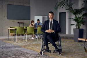 affärsman i en rullstol kommandon uppmärksamhet, symboliserar elasticitet och Framgång mitt i en dynamisk modern kontor miljö. foto