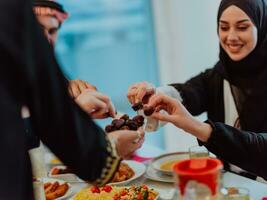 modern multietnisk muslim familj delning en skål av datum medan njuter iftar middag tillsammans under en ramadan fest på Hem foto