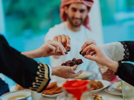 modern multietnisk muslim familj delning en skål av datum medan njuter iftar middag tillsammans under en ramadan fest på Hem foto