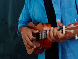 indisk ung man i en blå skjorta och glasögon spelar de gitarr i främre av de skola svarta tavlan foto