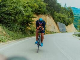 full längd porträtt av ett aktiva triathlete i sportkläder och med en skyddande hjälm ridning en cykel. selektiv fokus foto