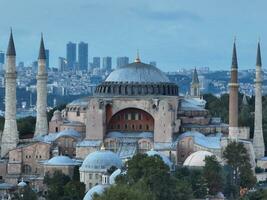 upprättande kretsande antenn Drönare skott av en hagia sophia helig stor moské med bosphorus bro och stad horisont med en flagga på de bakgrund i fatih, istanbul, Kalkon på solnedgång. foto