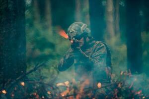 en soldat kämpar i en krigsskog område omgiven förbi brand foto