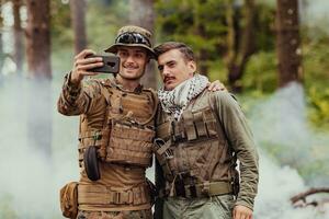 team av soldater och terrorist tar selfie med smartphone i de skog foto