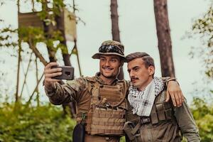 team av soldater och terrorist tar selfie med smartphone i de skog foto