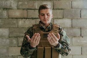 en muslim soldat av de särskild krafter ber till Gud förbi höjning hans händer och börjar en bön foto