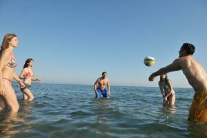 ung människor grupp ha roligt och spela strand volleyboll foto