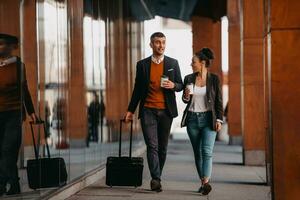 företag man och företag kvinna talande och innehav bagage reser på en företag resa, bärande färsk kaffe i deras händer.affärer begrepp foto