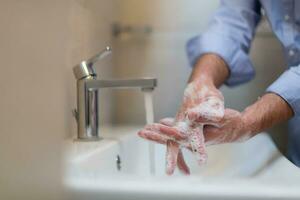 man använder sig av tvål och tvättning händer under de vatten knacka. hygien begrepp hand närbild detalj. foto