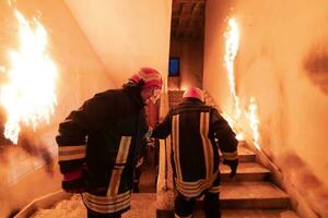 modig brandman gående övervåningen till spara och rädda människor i en brinnande byggnad. öppen brand och flamma. foto