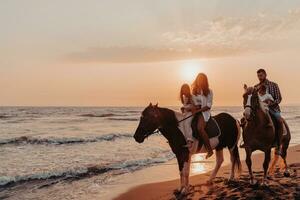 de familj spenderar tid med deras barn medan ridning hästar tillsammans på en sandig strand. selektiv fokus foto