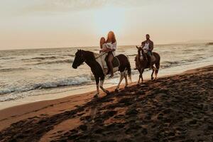 de familj spenderar tid med deras barn medan ridning hästar tillsammans på en sandig strand. selektiv fokus foto