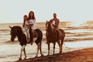 de familj spenderar tid med deras barn medan ridning hästar tillsammans på en sandig strand. selektiv fokus foto