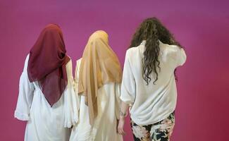 grupp porträtt av skön muslim kvinnor två av dem i modern klänning med hijab isolerat på rosa bakgrund representerar modern islam mode och ramadan kareem begrepp foto