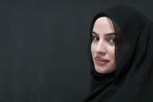 porträtt av skön muslim kvinna i modern klänning med hijab i främre av svart svarta tavlan representerar modern islam mode och ramadan kareem begrepp foto
