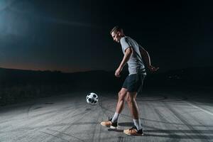 porträtt av en ung stilig fotboll spelare man på en gata spelar med en fotboll boll. foto