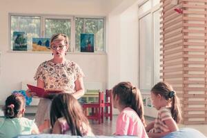 läsning tid i elementärt skola eller dagis, lärare läsning en bok till barn i elementärt skola eller dagis. selektiv fokus foto