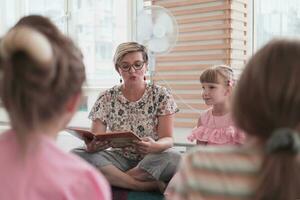 läsning tid i elementärt skola eller dagis, lärare läsning en bok till barn i elementärt skola eller dagis. selektiv fokus foto