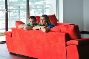 Lycklig par koppla av på röd soffa foto