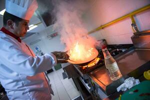 kock håller på med flambe på mat foto